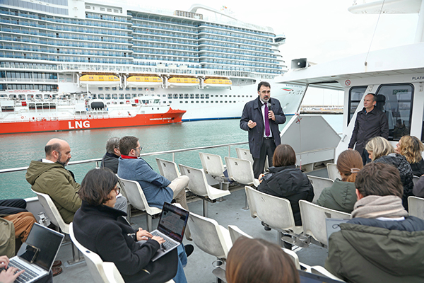 El presidente del puerto de Barcelona en la visita marítima donde explicó los resultados, al fondo la gabarra suministrando GNL a un crucero.
